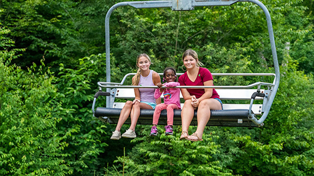 Three young girls taking a scenic chairlift ride on a nice summer day.